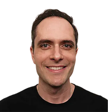 Smiling man with short dark hair wearing a black shirt against a transparent background.