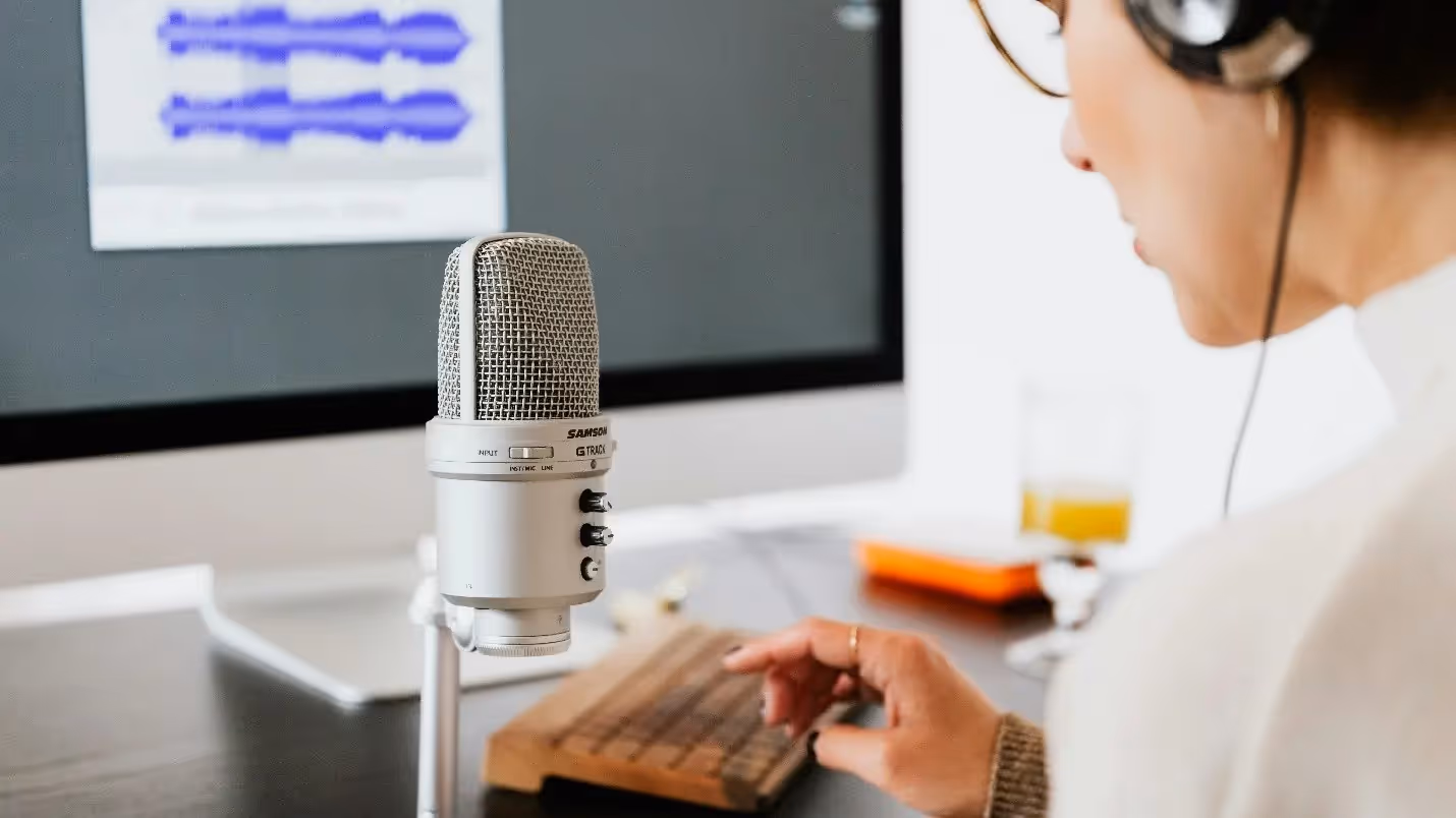 Person recording voiceover using studio microphone and audio waveform software