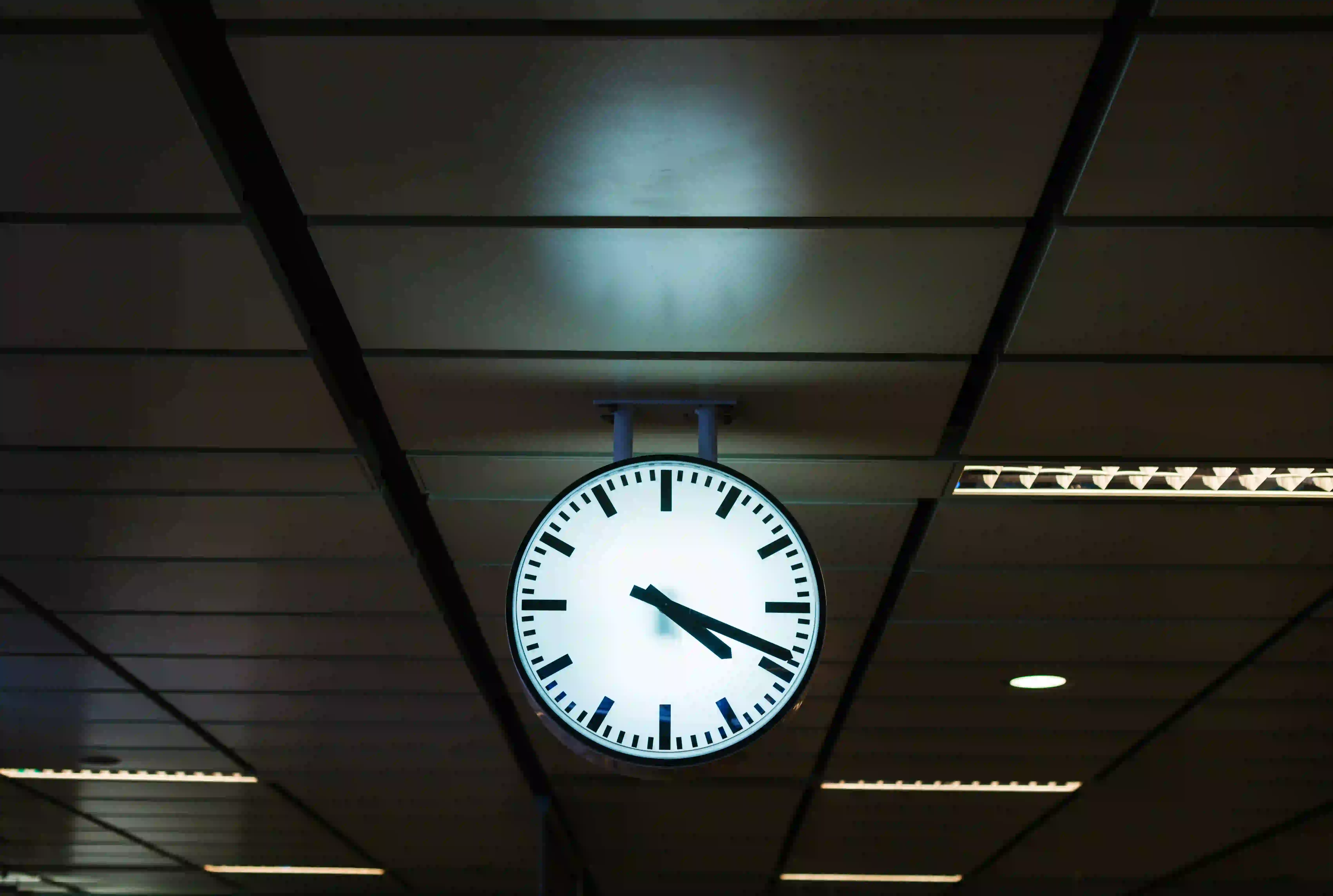 An analog clock hanging from a ceiling, representing global delivery models and timezone coverage for corporate video production.
