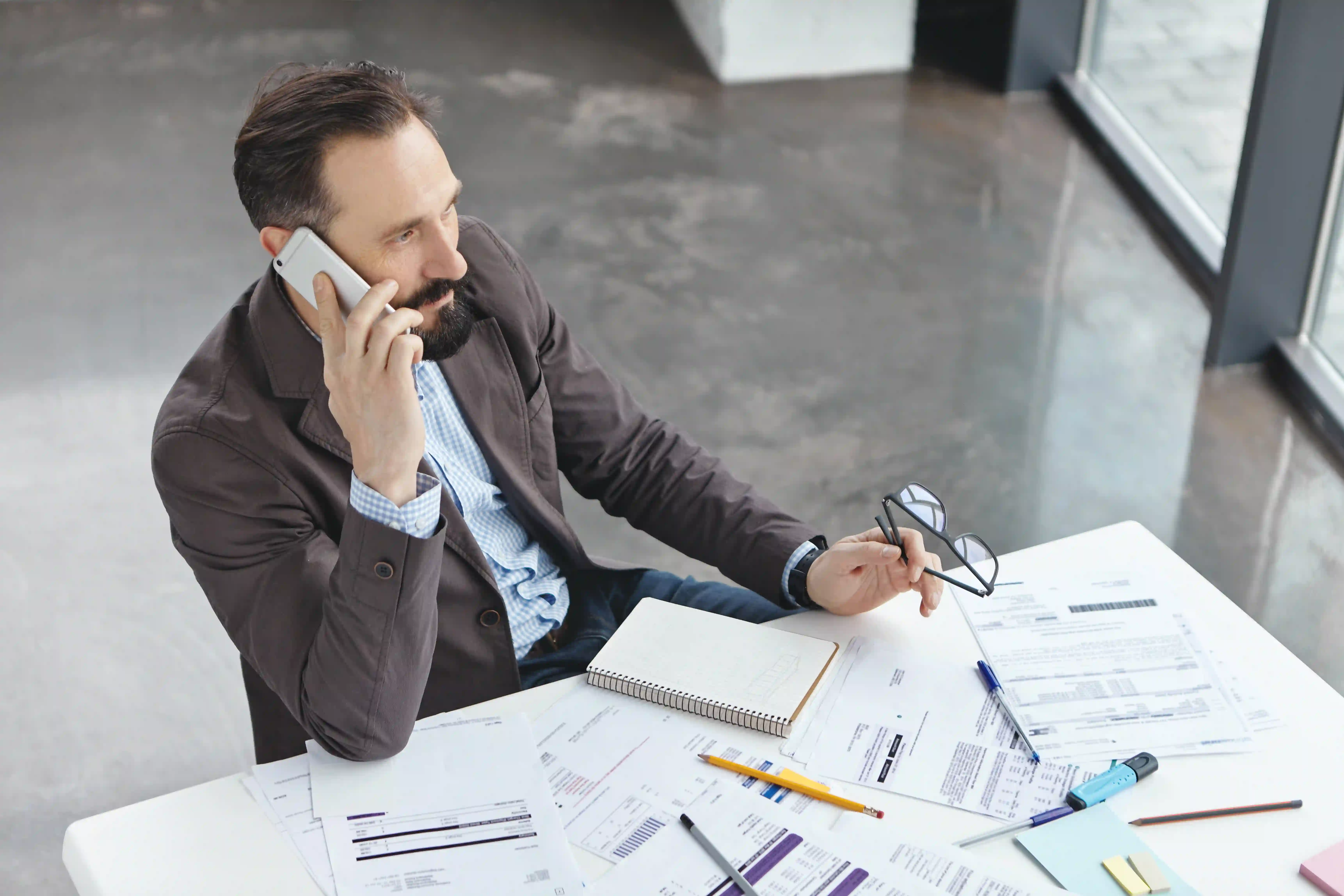 A corporate professional reviewing paperwork and making a call, representing the project management required when hiring an explainer video freelancer.
