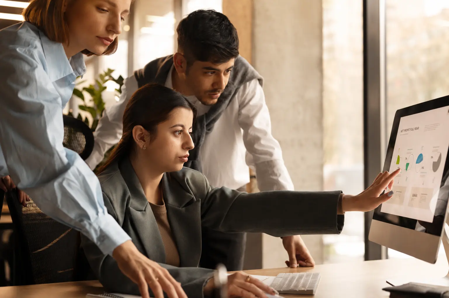 A corporate creative team analyzing content marketing KPIs and pipeline metrics on a desktop monitor in a modern office.