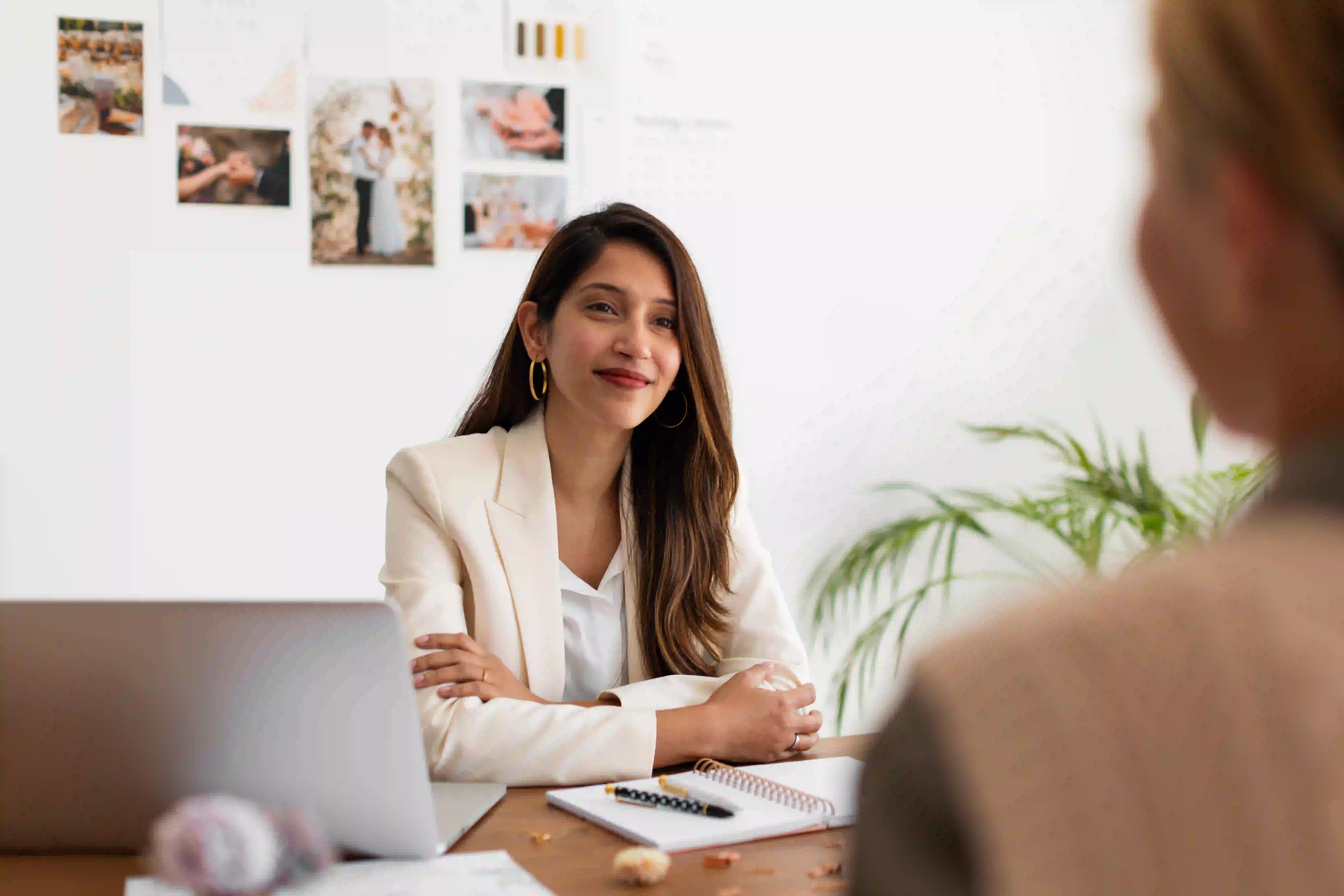 A professional woman in a white blazer smiling during a meeting, representing a positive candidate journey built on a strong employer brand strategy
