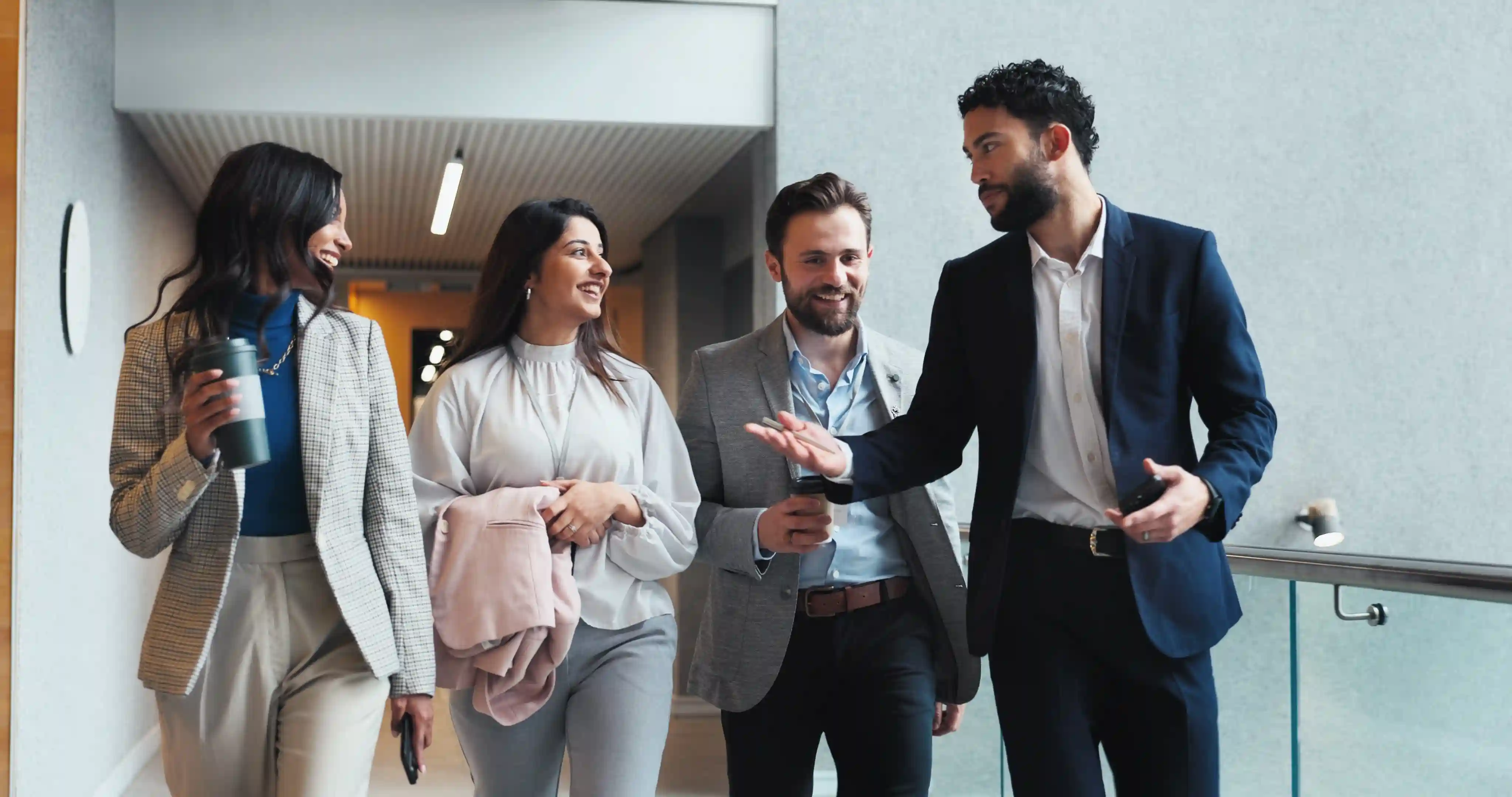 A diverse team of B2B professionals walking and talking in a modern office, illustrating how authentic workplace culture and employee voices build employer brand equity.