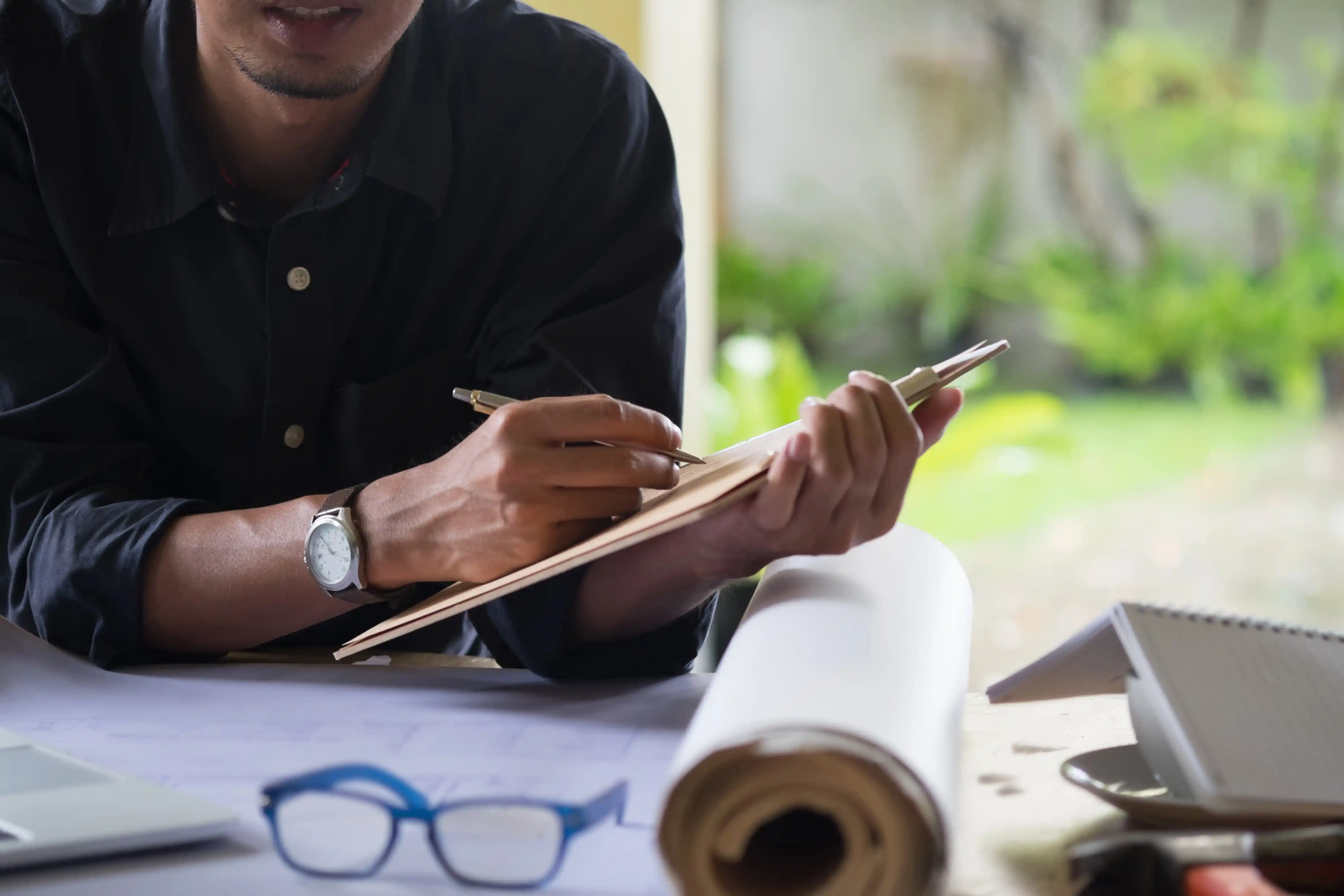 A marketing strategist writing notes and reviewing blueprints, illustrating a simple framework for building a 2027 B2B digital marketing plan.