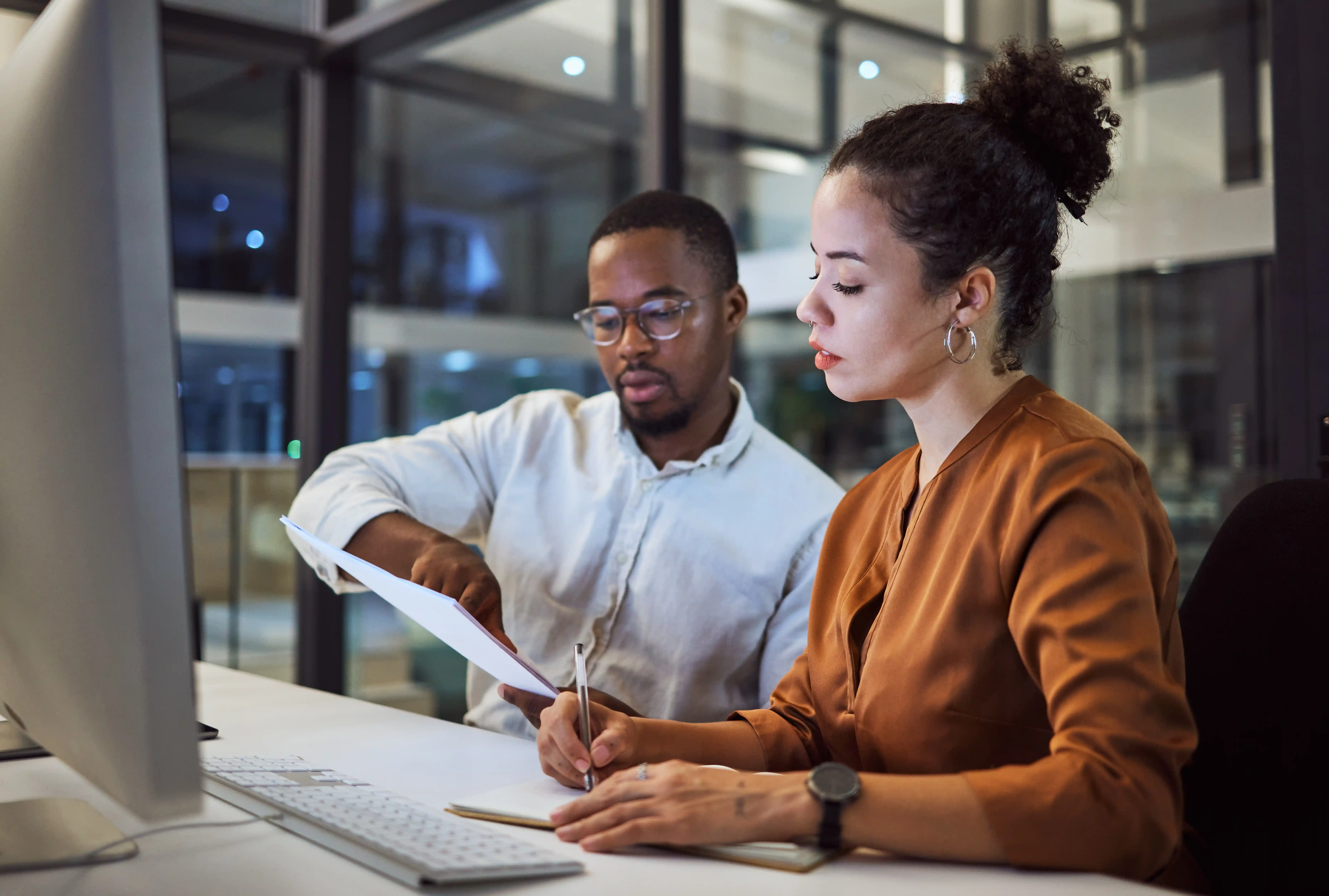 Two B2B marketers reviewing campaign data and documents at a desk, illustrating how to measure account engagement and sales signals in the first 90 days.