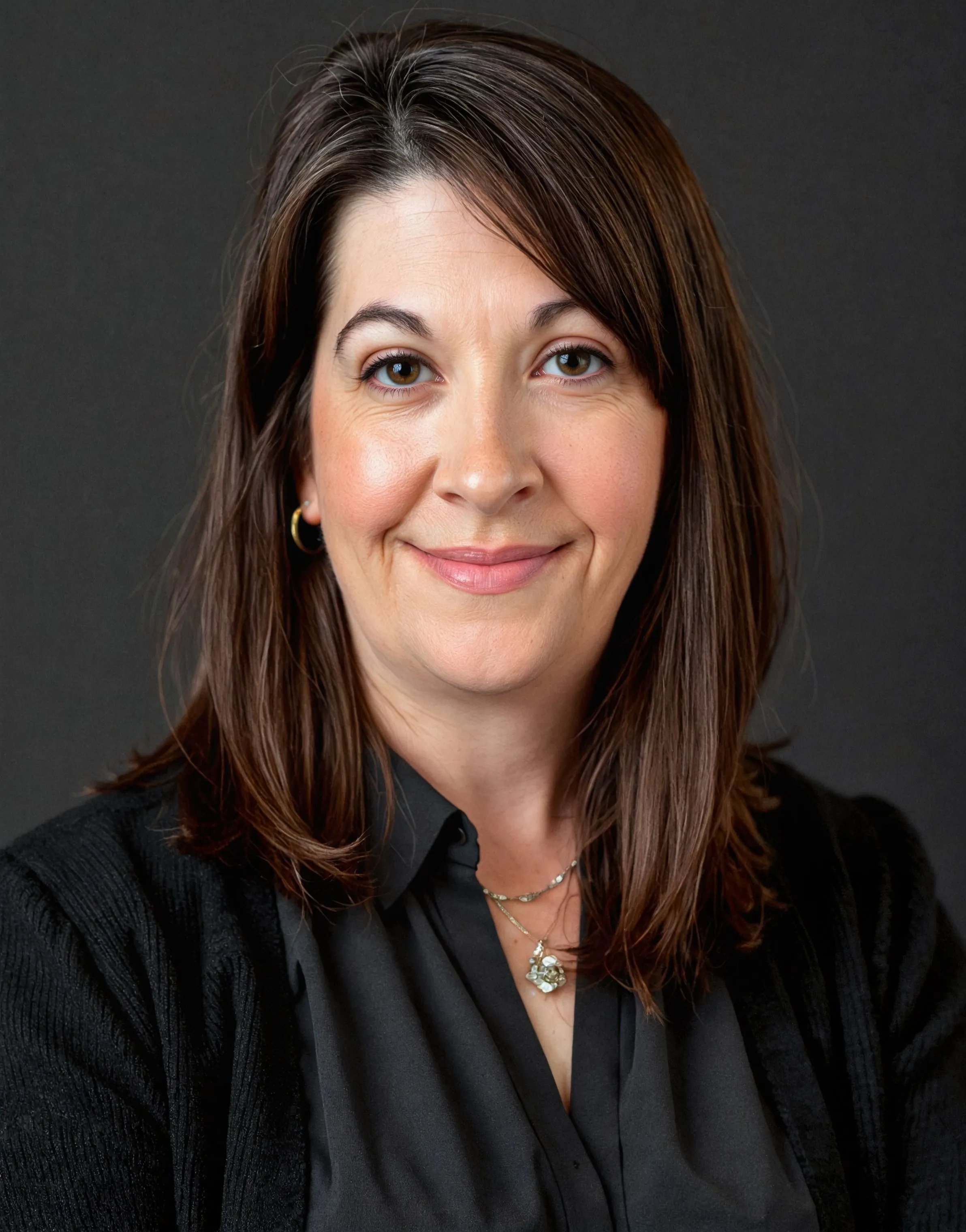 Professional headshot of Dr. Heather Buffington Anderson, Senior Advisor of Governance at MMC, a woman with shoulder-length dark brown hair wearing a dark top and a delicate necklace, smiling against a dark background.