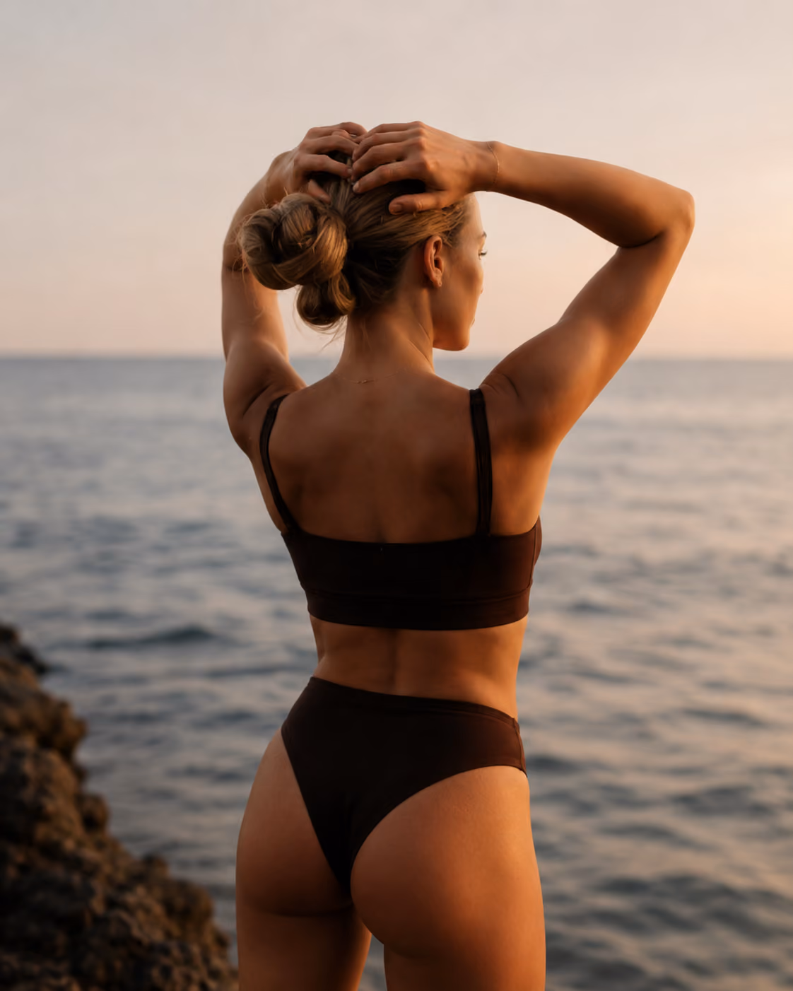 Woman with cfab shapewear on rocks with ocean in the background