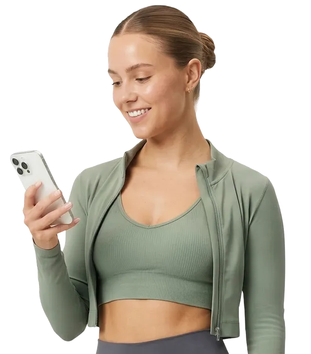 Smiling woman in green sportswear holding and looking at a smartphone.