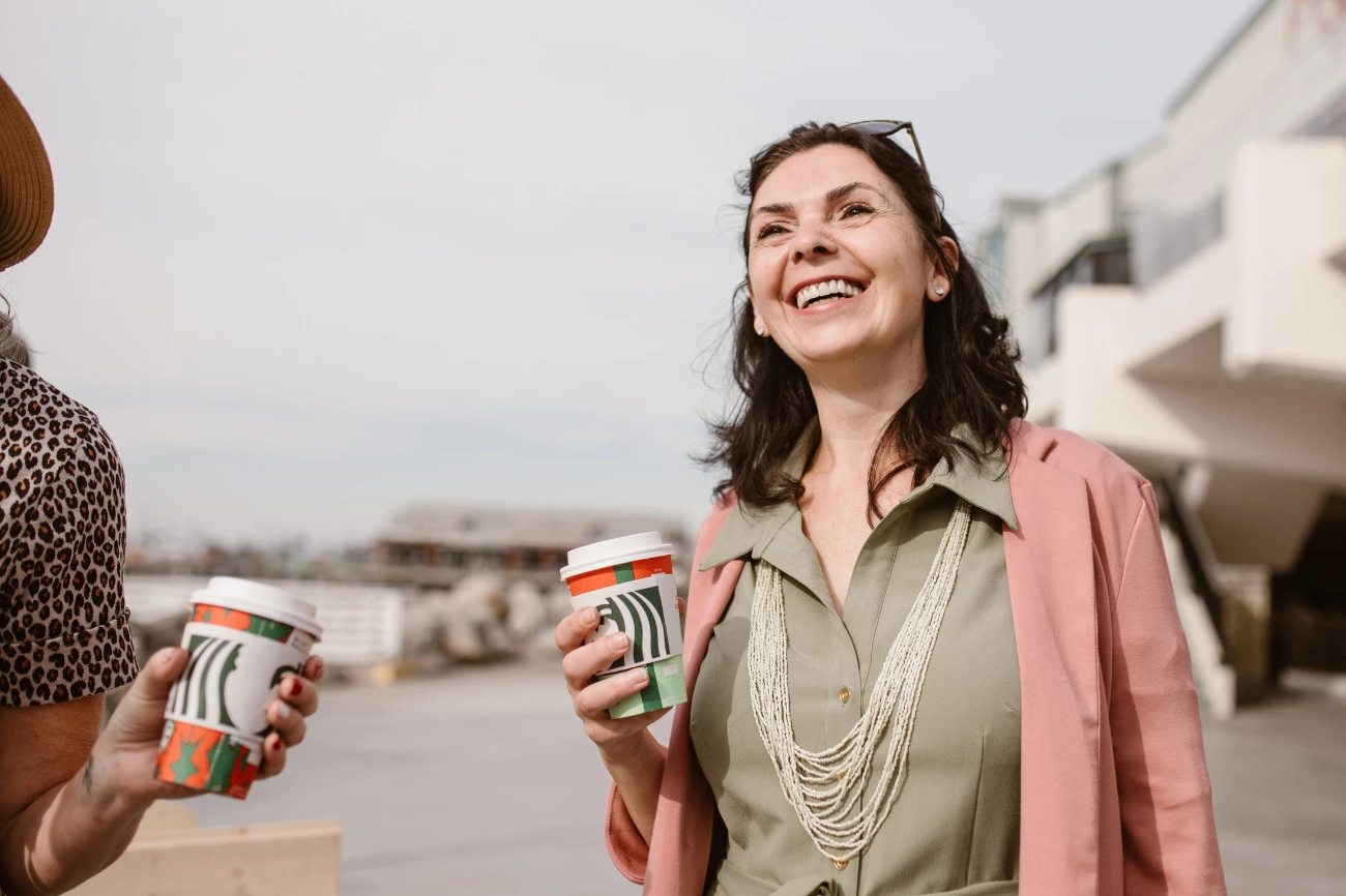 women in mid 30s holding a beverage on a walk