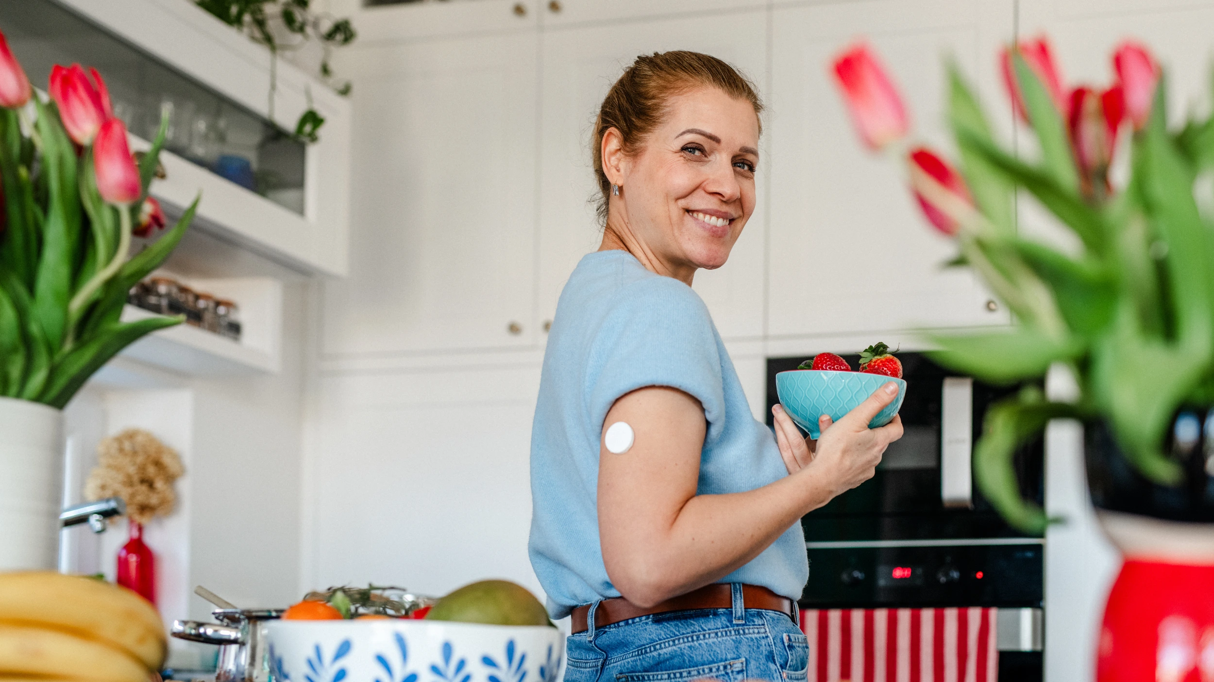 Women standing in kitchen with glucose monitor on