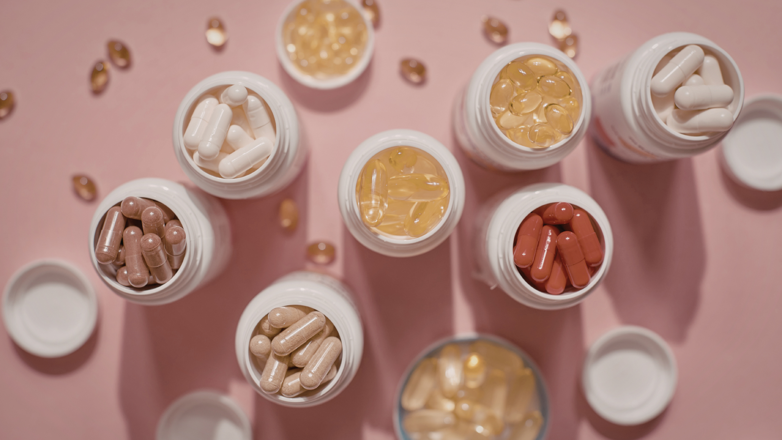 Many supplements on a pink table 