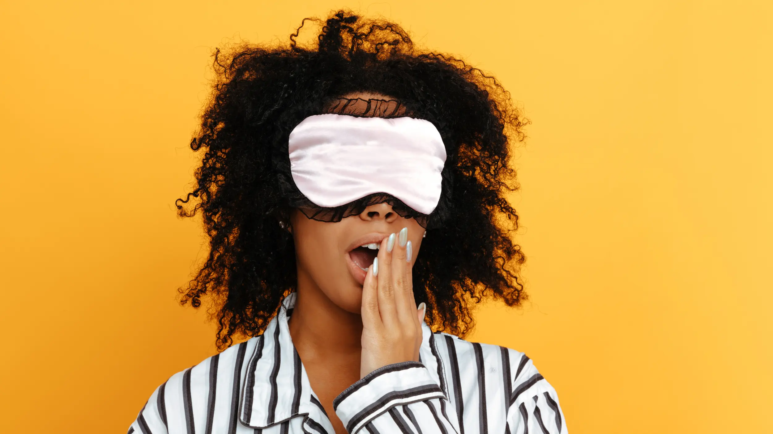 women in sleep mask yawning