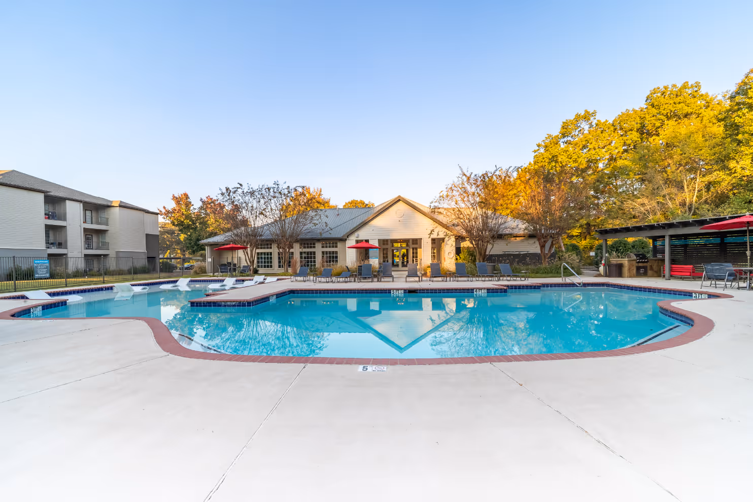 Wide view of Swimming pool with lounge chairs and view of clubhouse 