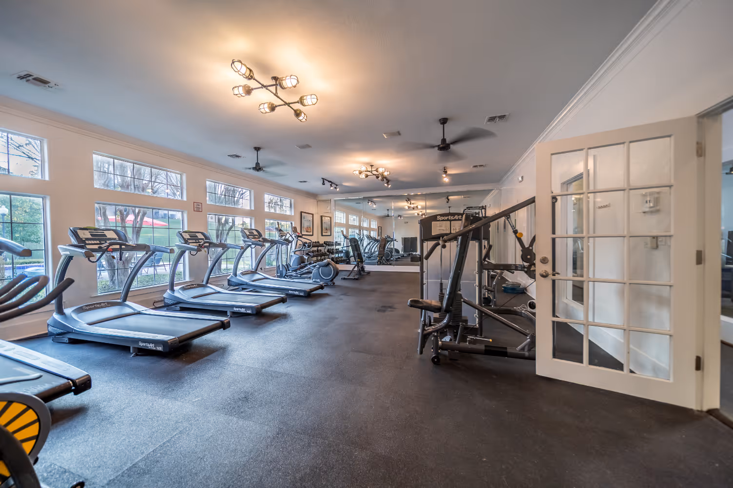 Gym featuring treadmills, full mirrored wall, and large windows