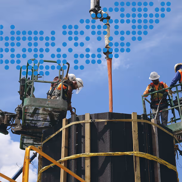 Workers on top of round forms pouring concrete