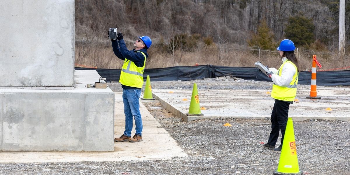 Workers conduct performance testing outside precast concrete structure.