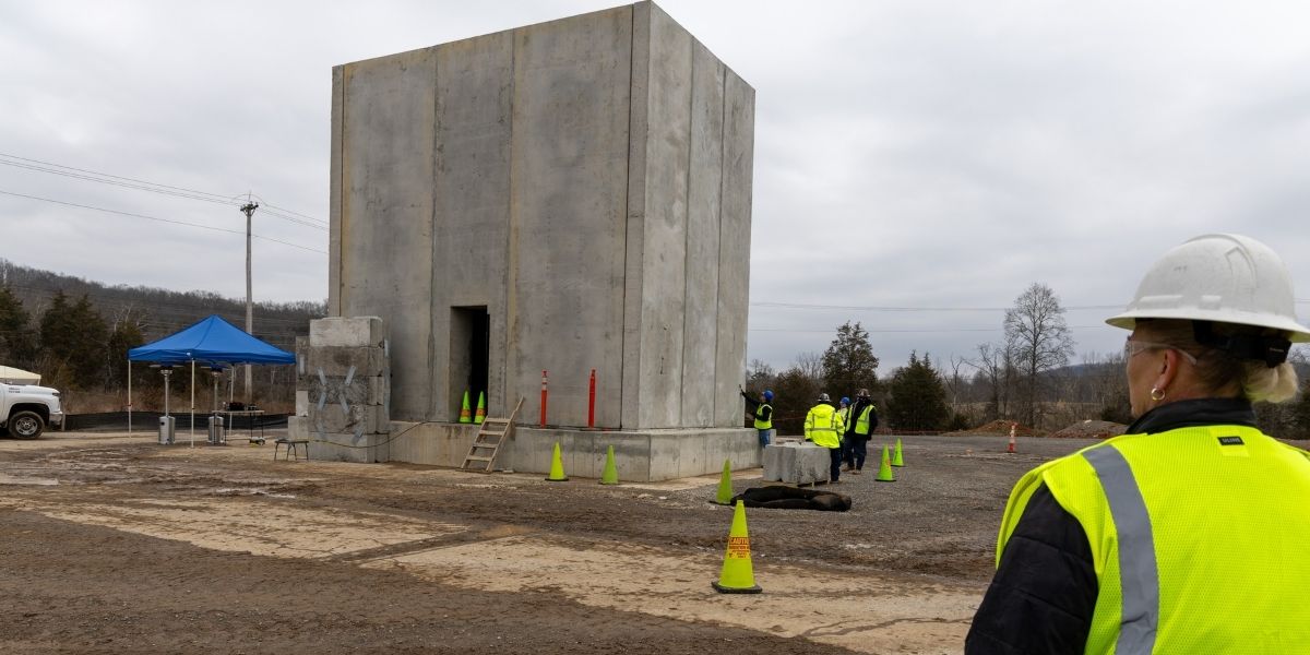 Worker looks in the distance at performance testing on precast concrete structure.