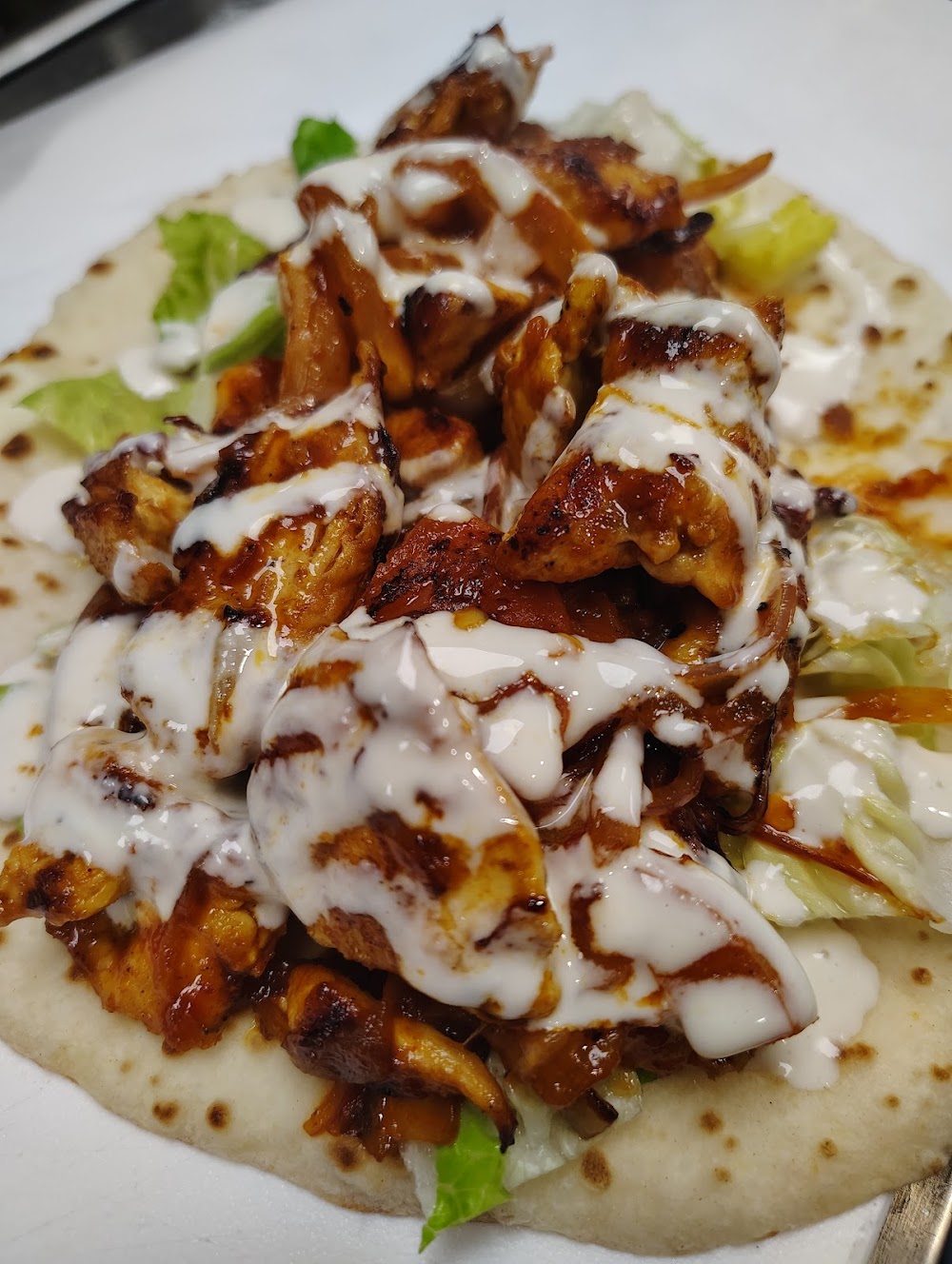 A delicious looking chicken dish with sauce and cheese on a tortilla.