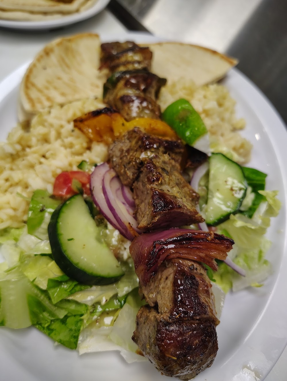 A plate of food with a meat skewer and vegetables.