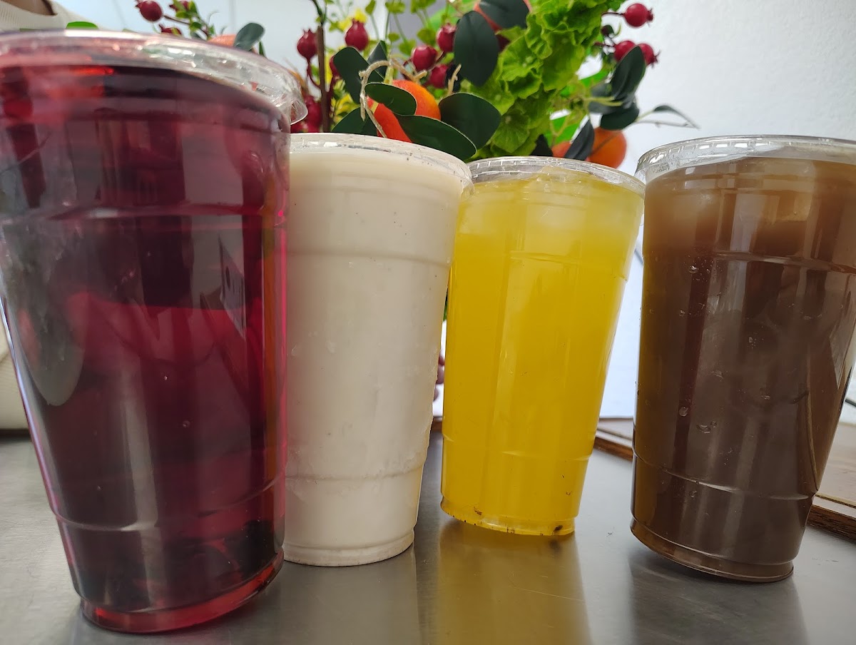 Three different colored drinks are lined up on a table.