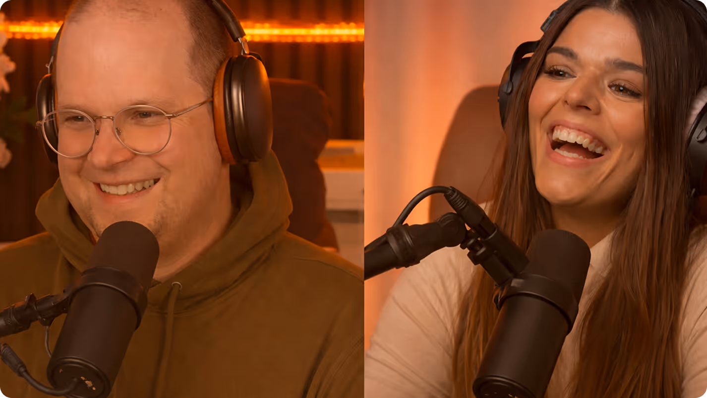 Zwei Menschen mit Kopfhörern sprechen fröhlich in Mikrofone in einem Aufnahme- oder Podcaststudio.