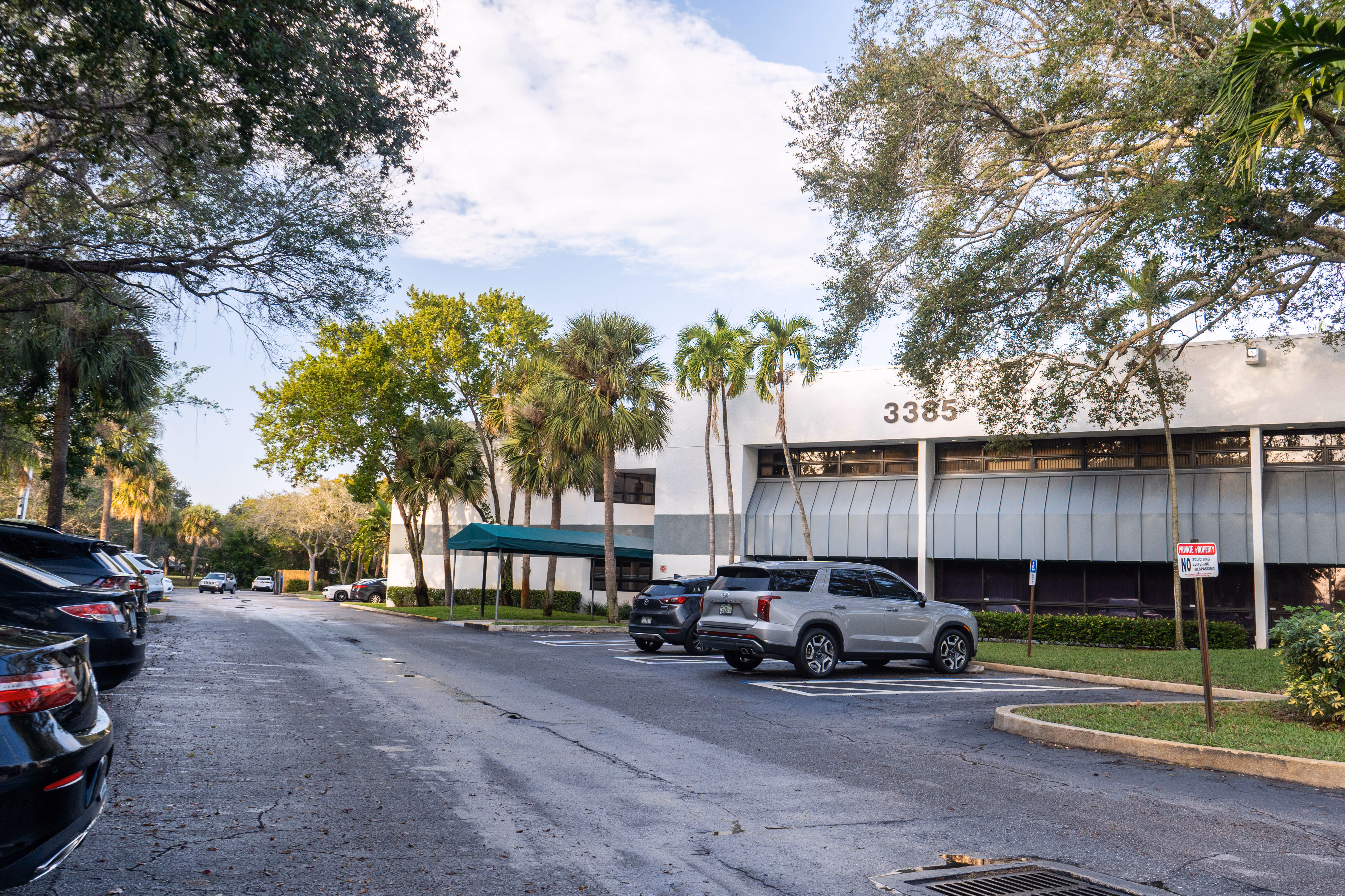 Parking lot with cars in front of Smile Associate's dental office in Palm Beach Gardens.
