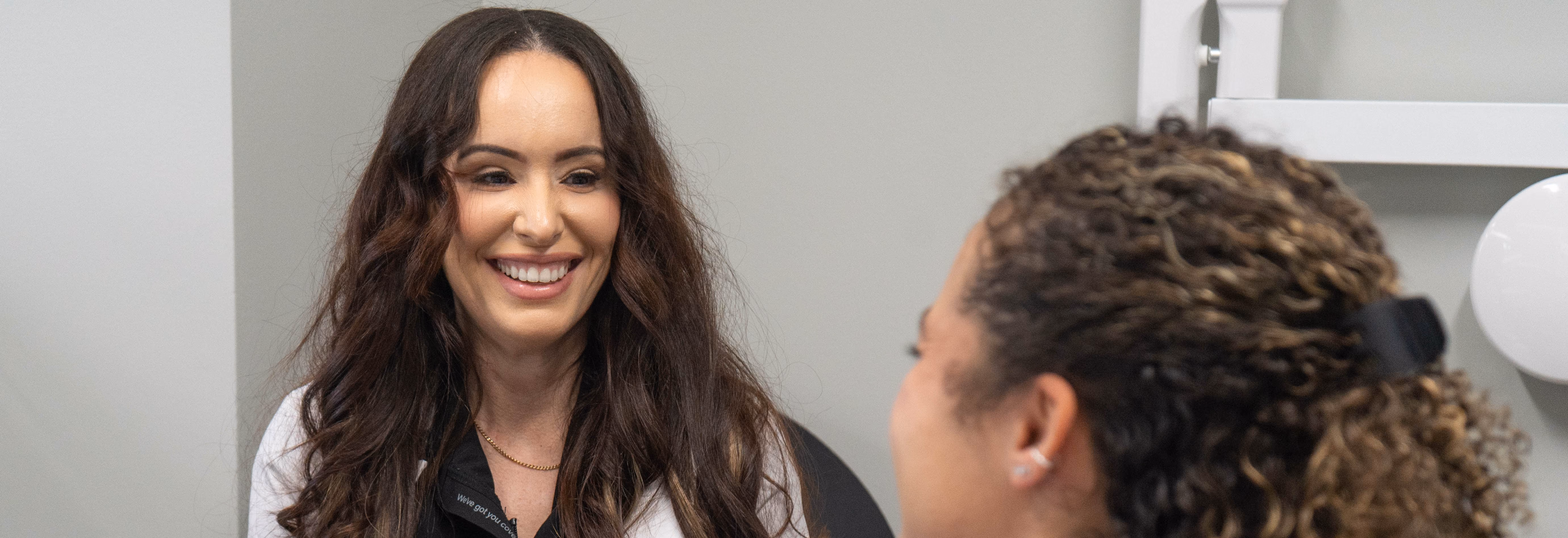 Smiling woman with long brown hair talking to another person at Smile Associate's dental office in South Palm Beach.