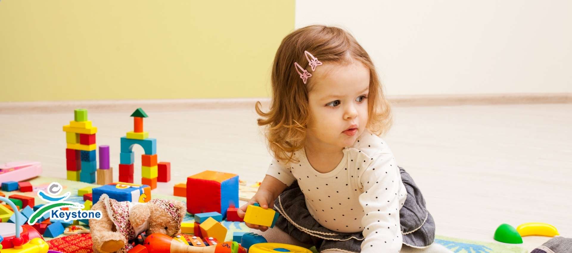 Nursery toddler on a play mat playing with coloured bricks