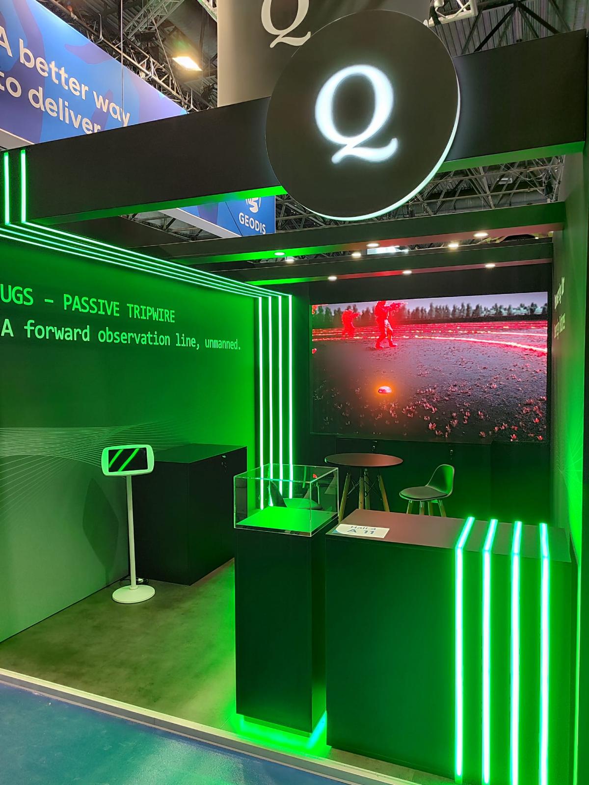 Exhibition stand with green LED lighting, digital product display and branded counter