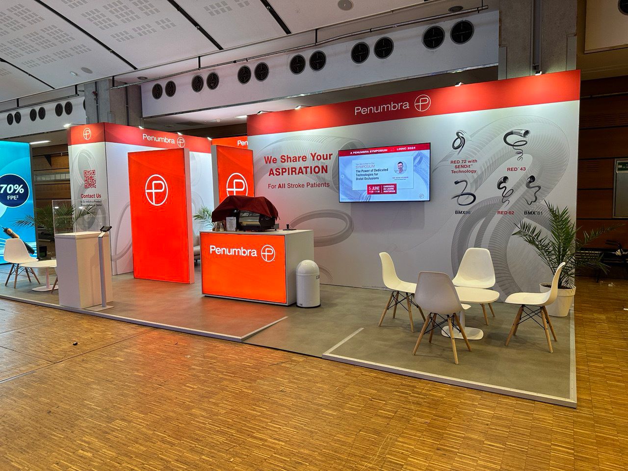 Exhibition stand with branded product displays, digital screen and meeting area