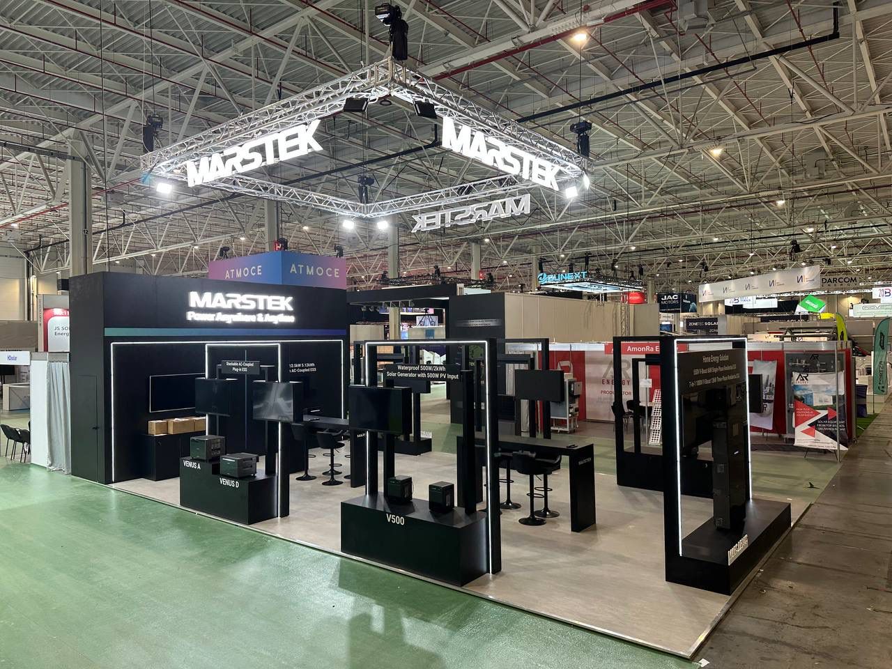 Large exhibition stand with overhead branding, product displays and meeting areas