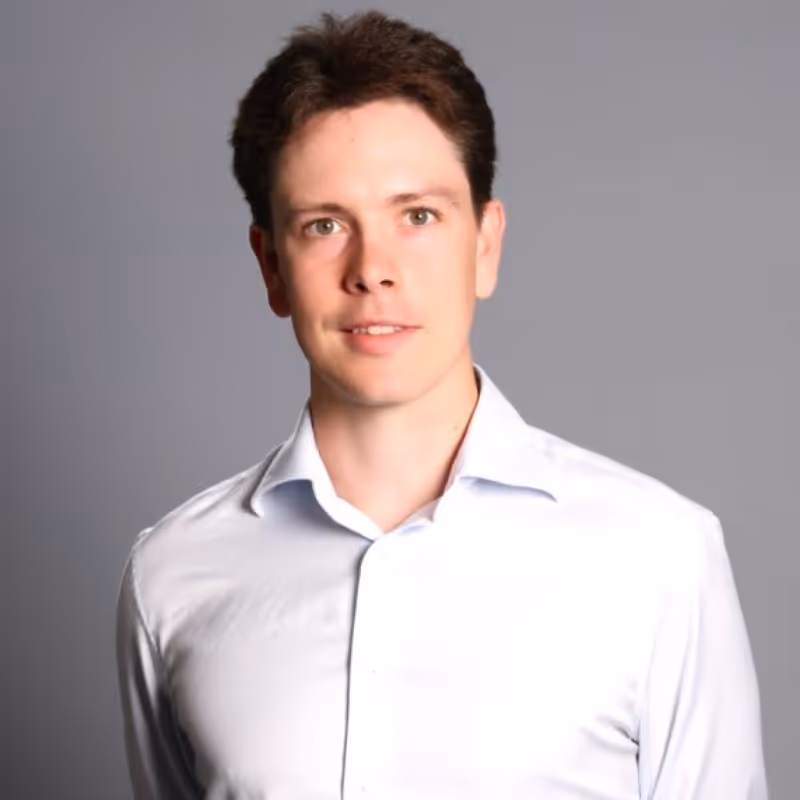 A businessman in a white shirt looks confidently into the camera against a gray background. GLG, placed with Runlayer. Text overlay reads “Education: Cornell University, Past Company: GLG.