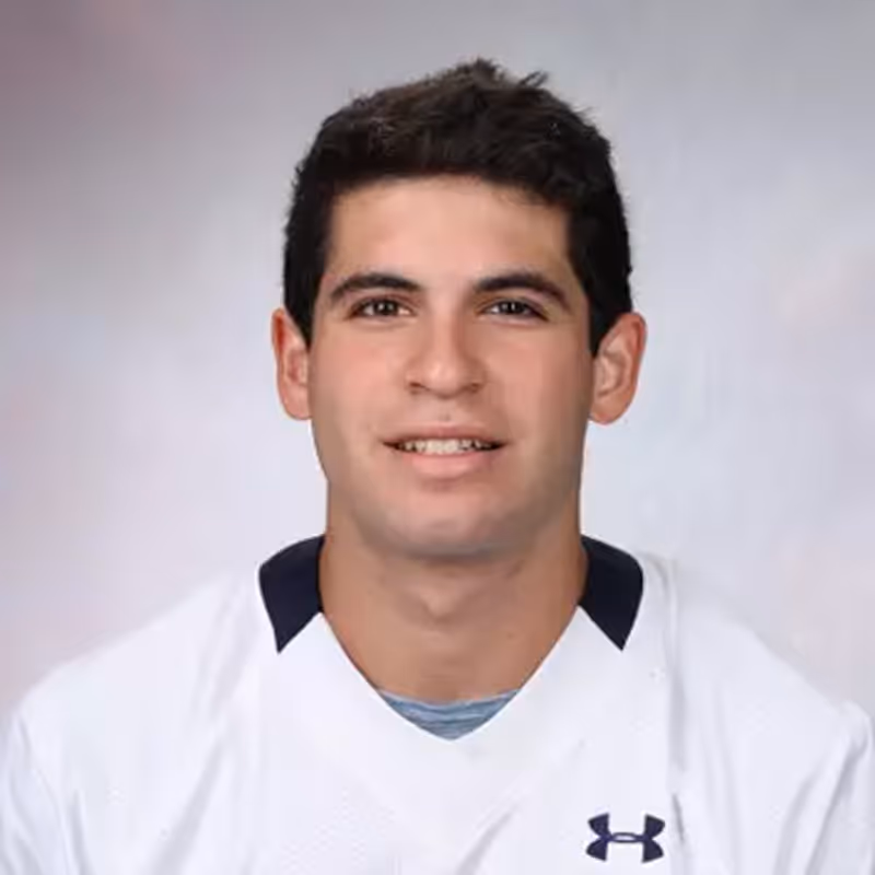 A young man with short dark hair smiles slightly, wearing a collared shirt. The background is light gray.. Previously with Encore Finance Capital, placed with Shield AI.
