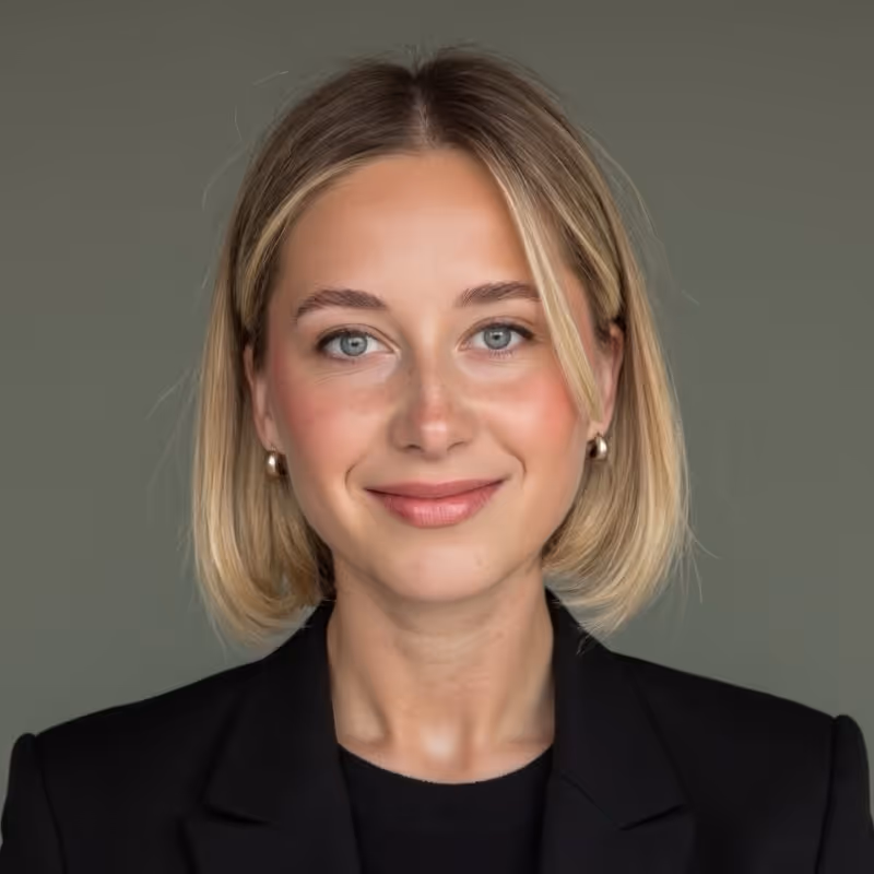 A blond female in professional attire with a small smile.