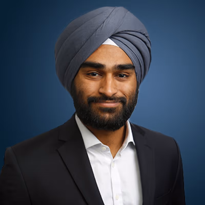 Professional man in a turban in a white shirt and brown jacket, blue background. 