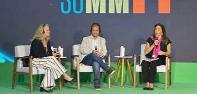 Três pessoas sentadas em cadeiras brancas participando de um painel de discussão em um evento chamado SUMMIT.