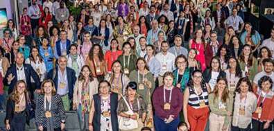 Grande grupo de pessoas posando para foto em evento, todas olhando para a câmera e sorrindo.