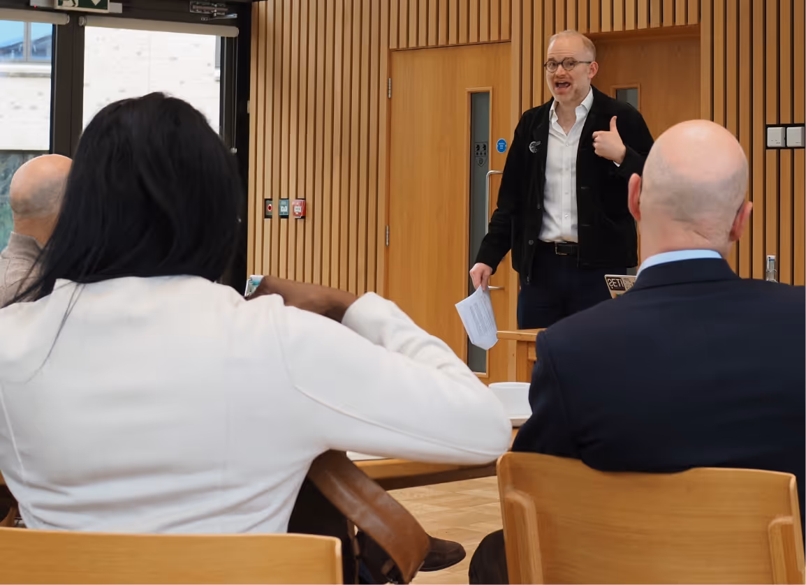 In a Thompson Harrison leadership workshop, a middle aged white man in a blazer and glasses talked to a group