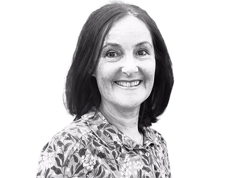 Tracey Camilleri headshot in black and white. Tracey has blonde shoulder length hair and is wearing glasses