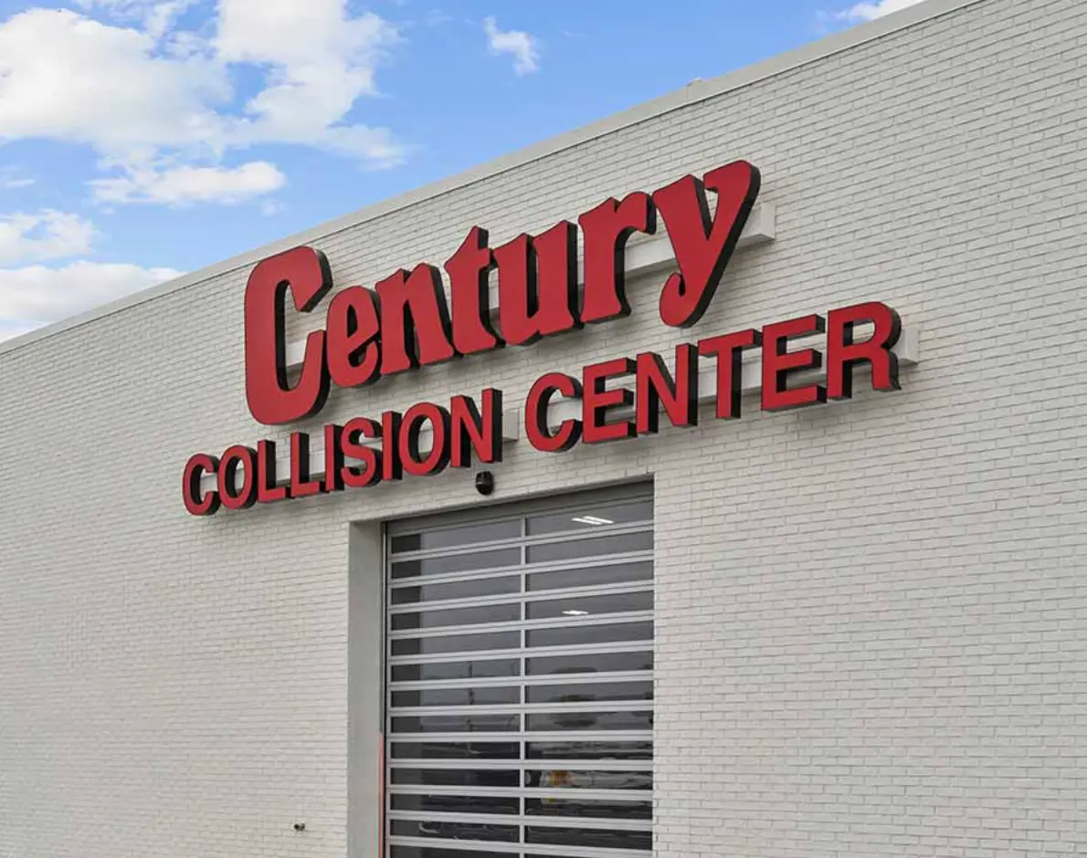 Closeup of the Century Collision Center sign on a white brick building.