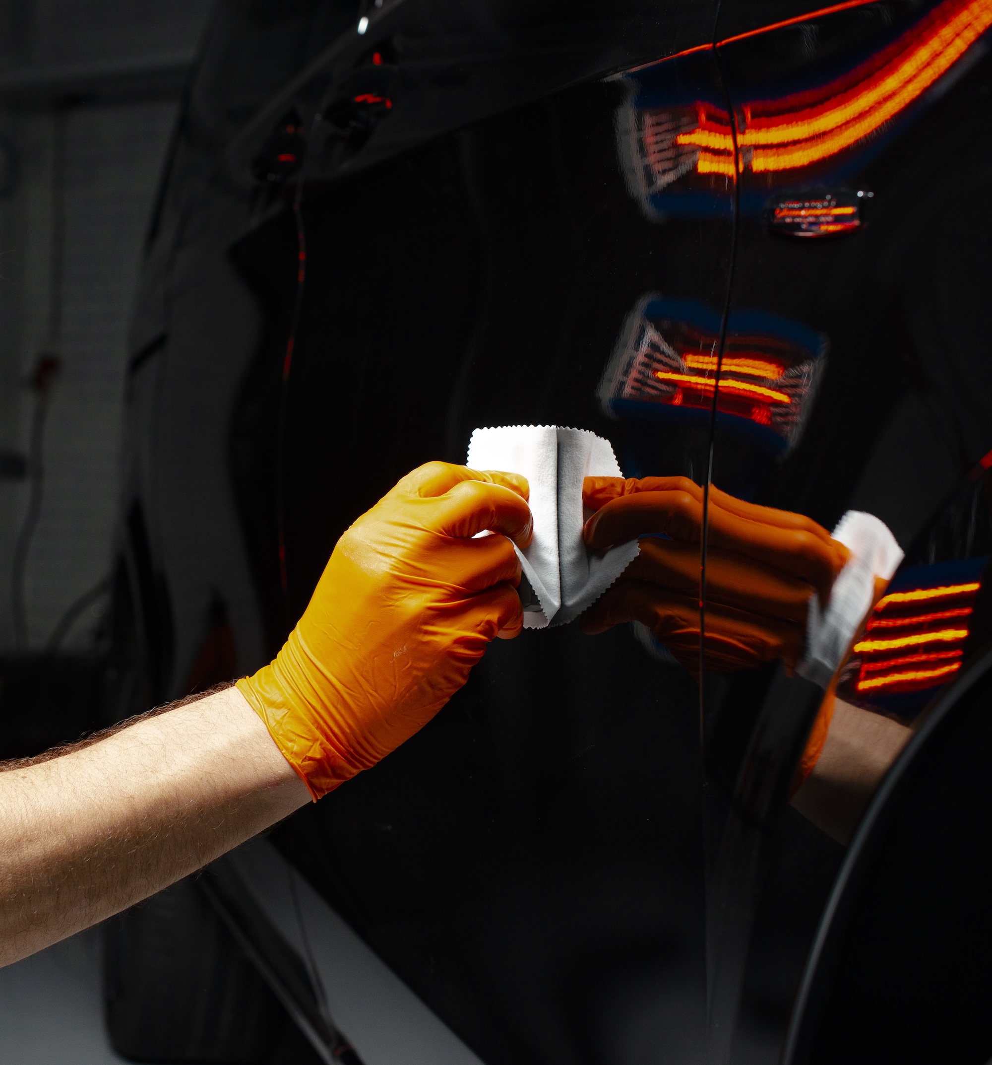 Closeup of a collision repair professional applying film to the panel of a car door.
