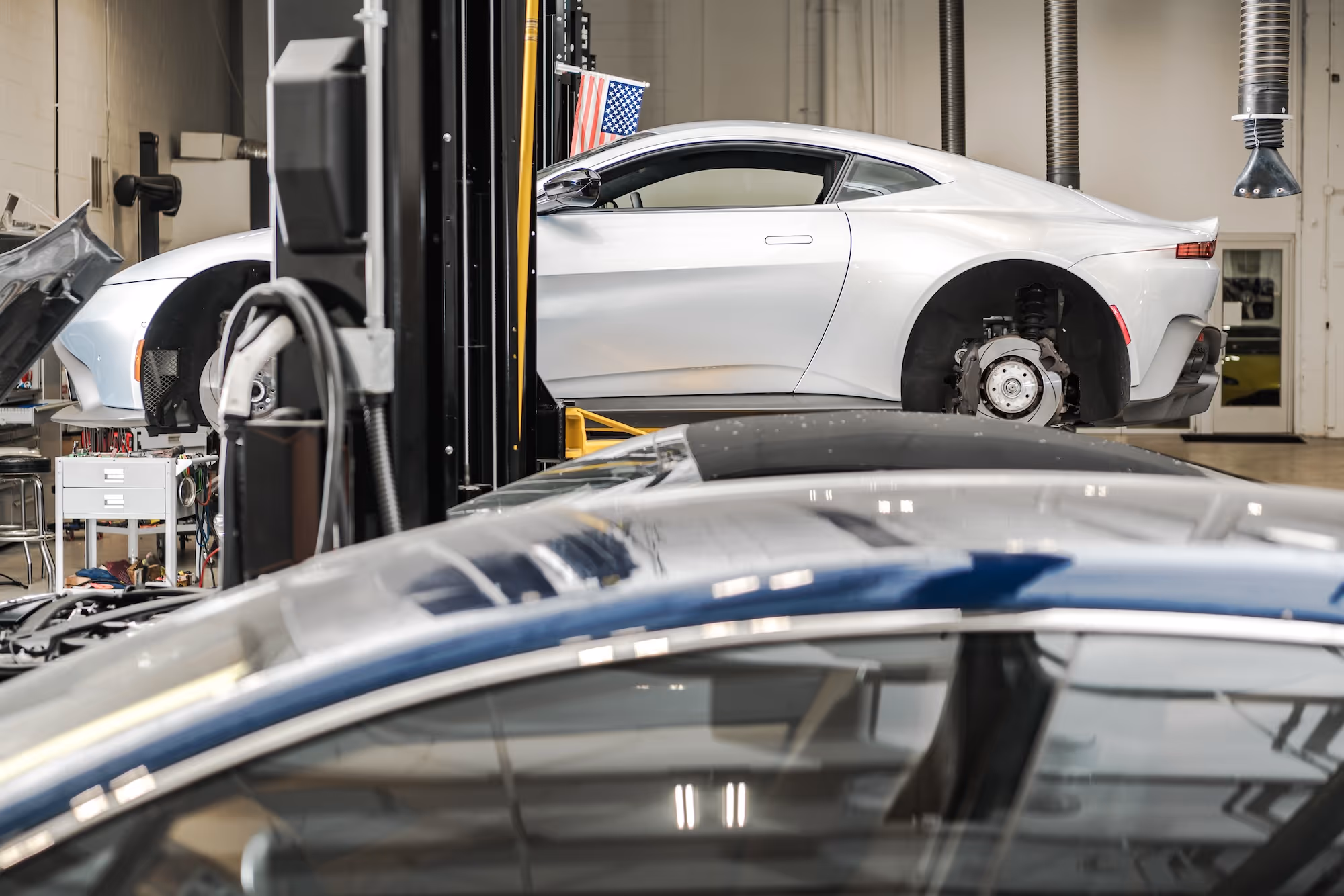 White coupe in a repair bay on the repair center floor.