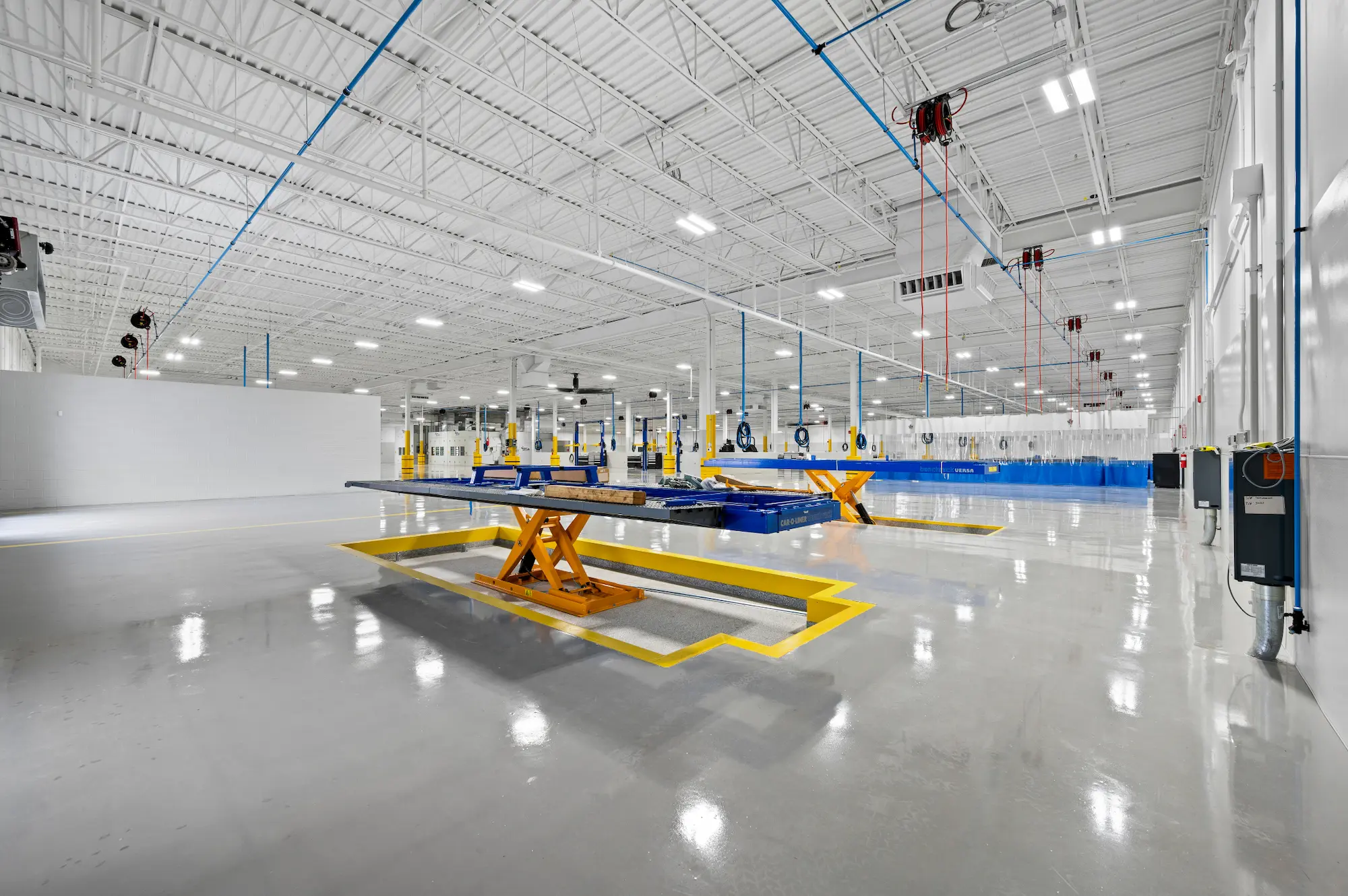 Car lifts and repair stations on the shop room floor at Century Collision Center.