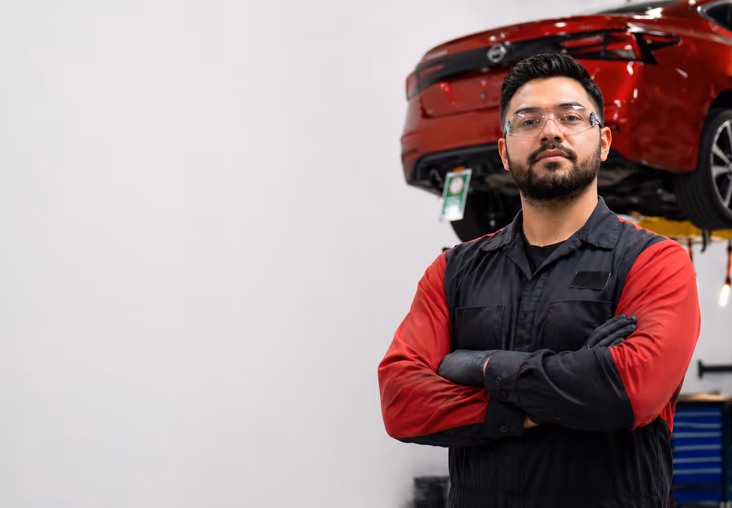 Collision repair professional with arms folded in front of a collage of vehicles and tools.
