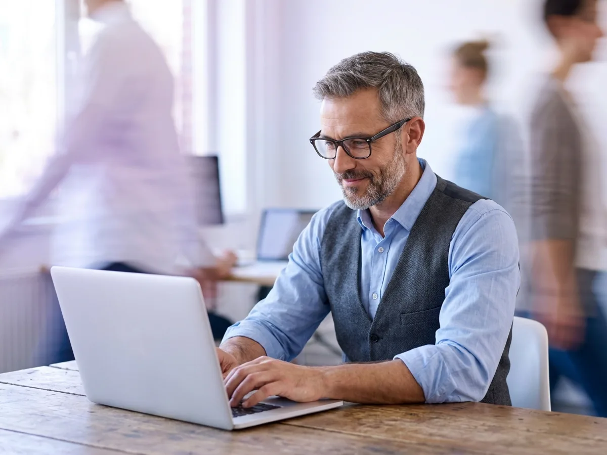 Contador de óculos analisando no notebook o crédito de IBS e CBS das compras de um cliente na Reforma Tributária