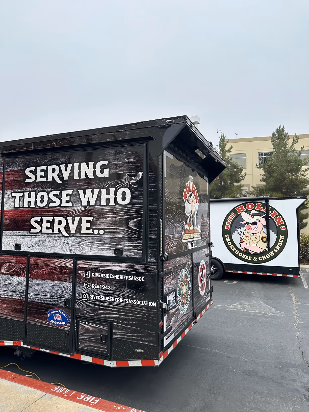 Food trailers with branding for Riverside Sheriff's Association and RSA's Rollin' Smokehouse & Chow Shack parked in a lot.