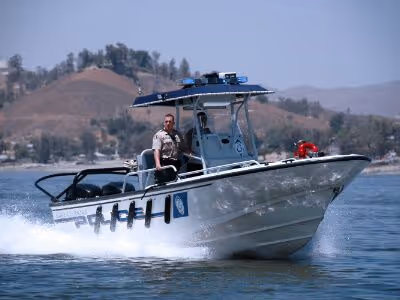 A Riverside County Sheriff's deputy piloting a patrol boat at high speed on a lake.