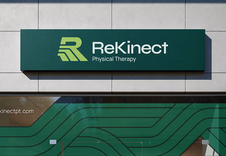Green and dark green sign on a building reading 'ReKinect Physical Therapy' with a stylized letter 'R' logo on the left.