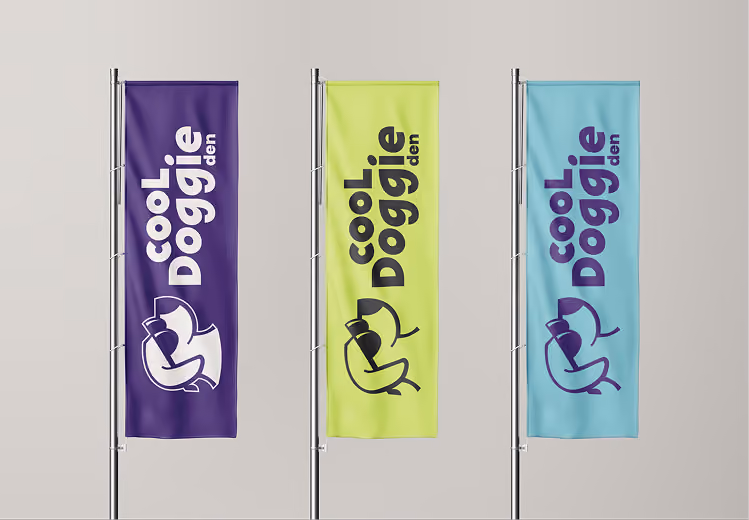 Three vertical flags on poles, each with a stylized dog wearing sunglasses logo and the text 'COOL Doggie den' in bold letters; the flags are purple, lime green, and light blue from left to right.