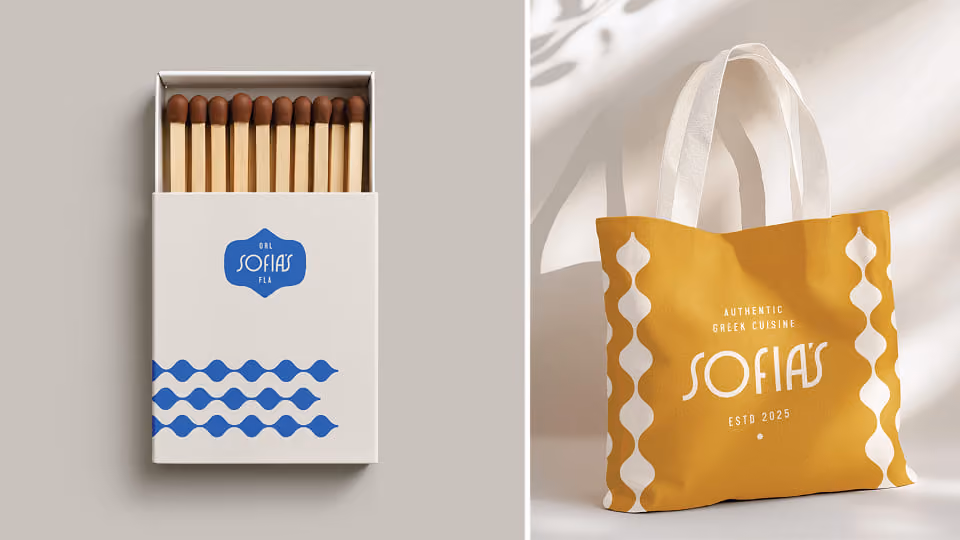 Two branded items: on the left, an open matchbox with long wooden matches and a white cover featuring blue wavy lines and a logo reading 'GRL SOFIAS FLR'; on the right, a mustard yellow tote bag with white handles, white wavy side patterns, and the text 'AUTHENTIC GREEK CUISINE SOFIAS ESTD 2025'.